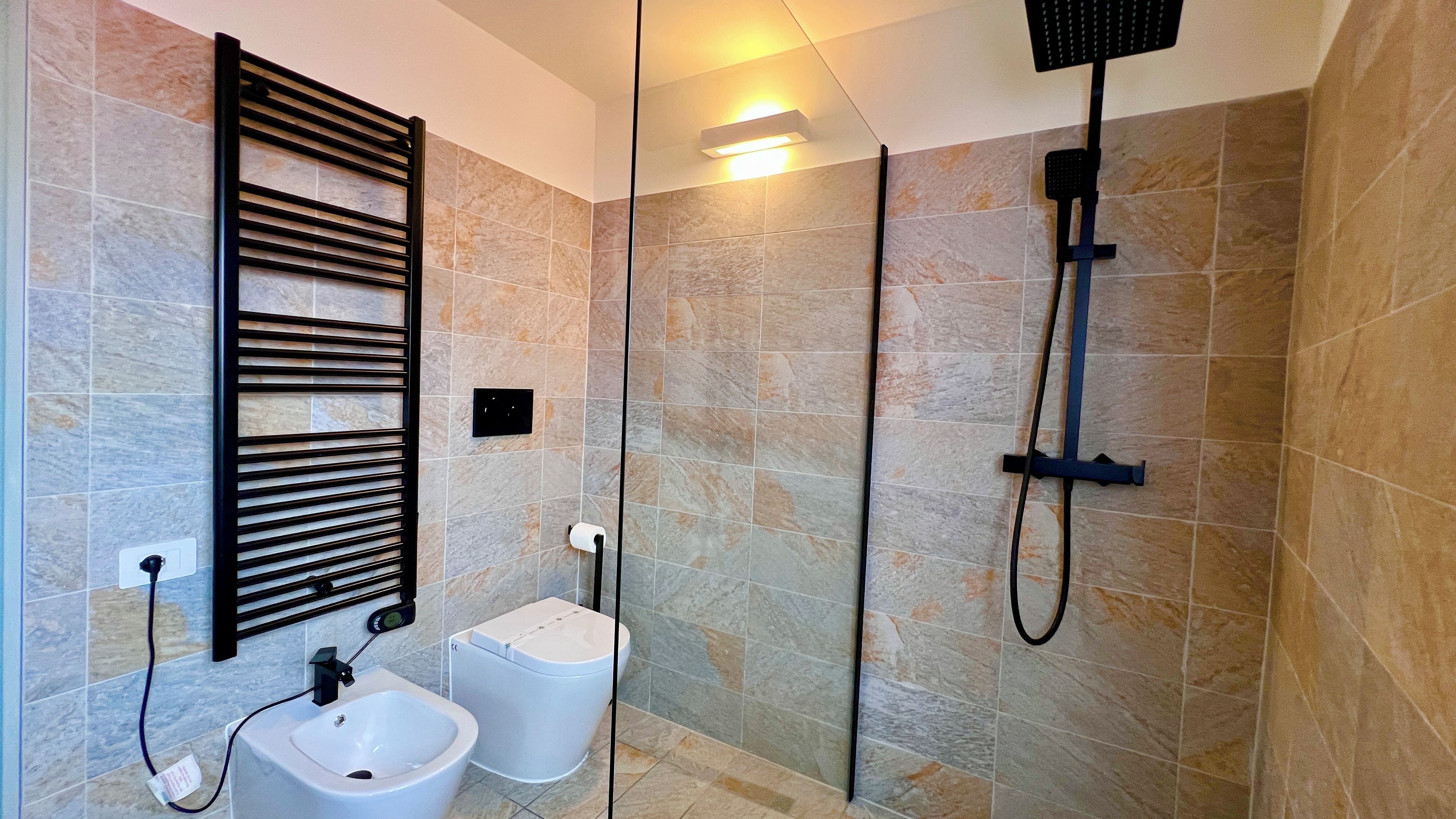 A modern bathroom with a towel rack, a bidet, and a shower.