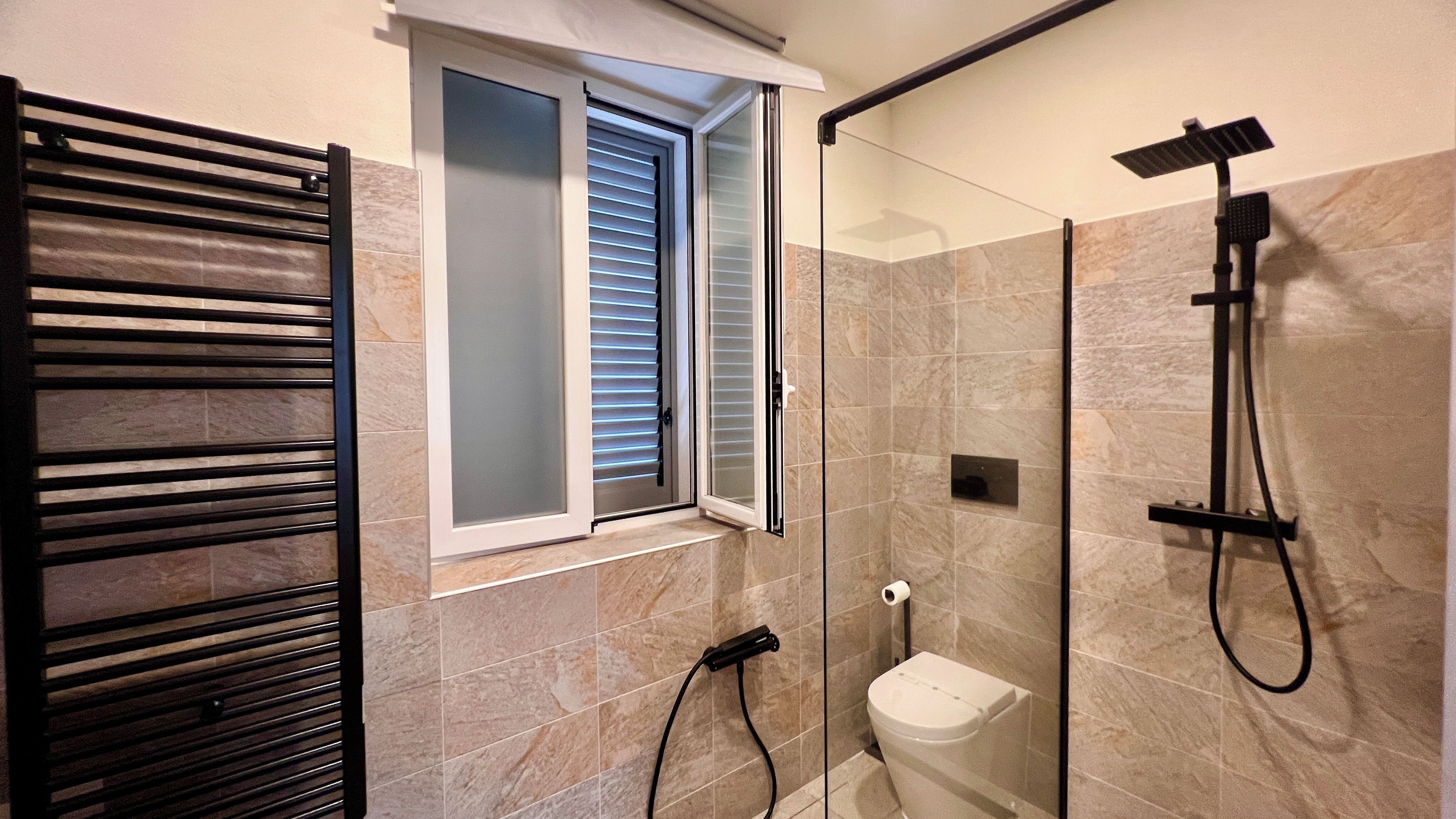 Un baño moderno con cabina de ducha de vidrio, un perchero y un inodoro.