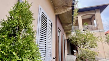 Un edificio con balcón, puerta y un pequeño jardín.