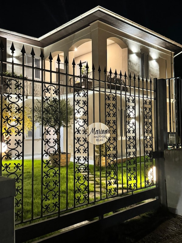 A gated property with a well-lit entrance, a sign with the name 'Marina,' and a landscaped garden area.