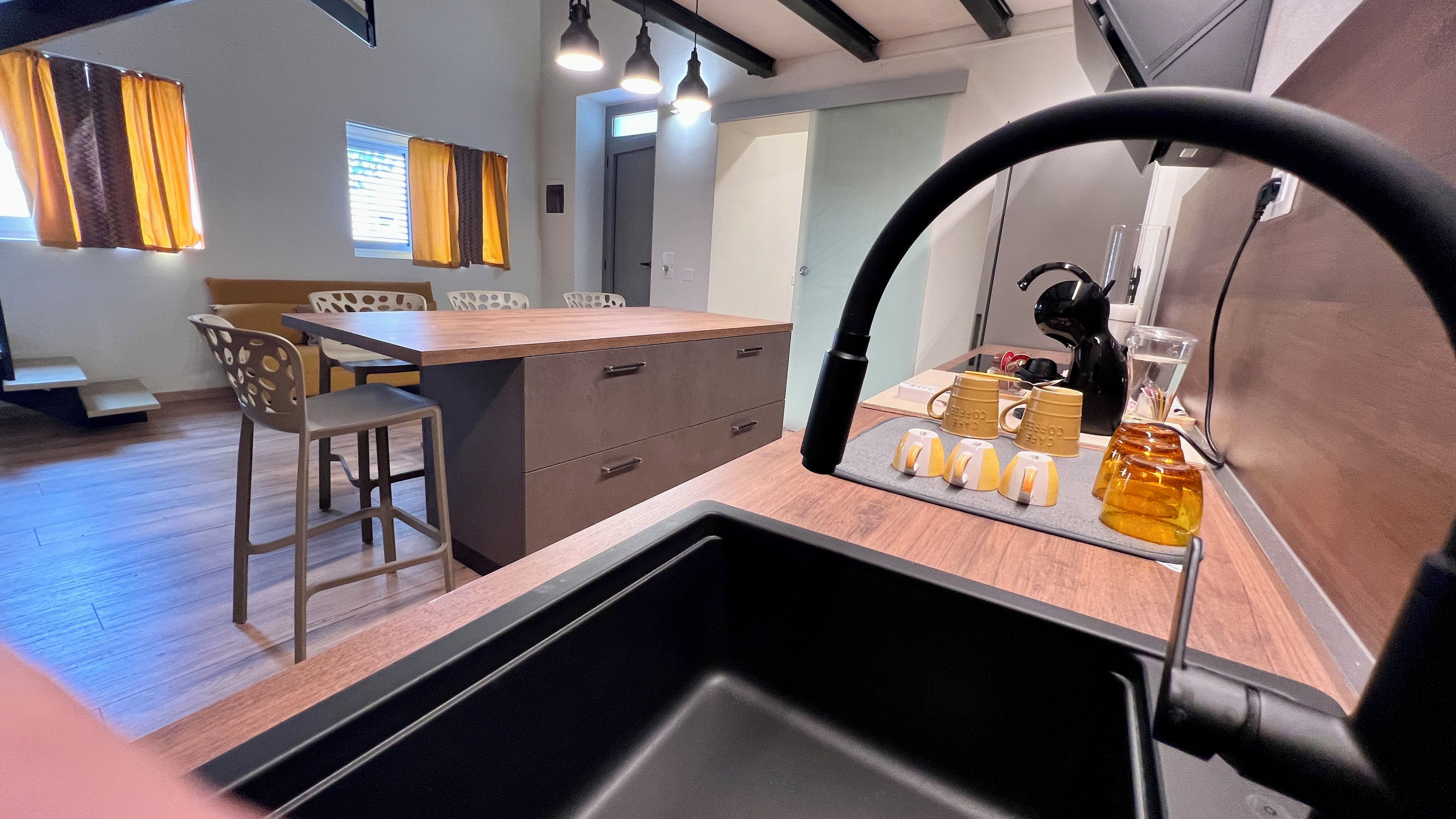 Una cocina moderna con encimera de madera, un fregadero y una estación de café con tazas y cafetera.