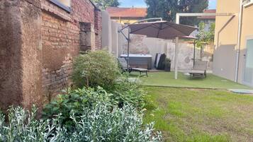 A backyard with a patio area, a hot tub, and a covered seating area.