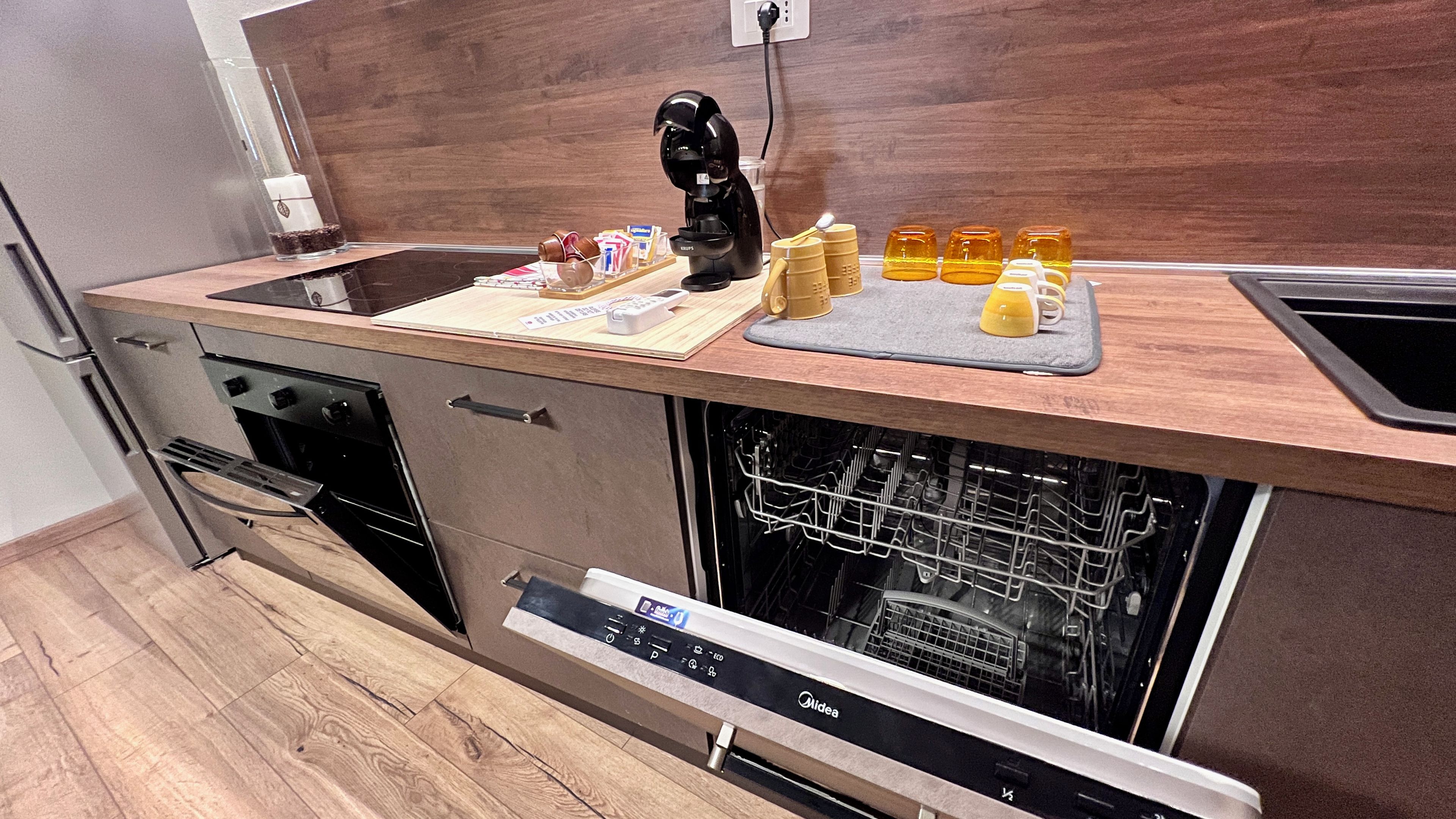 Una cocina moderna con lavavajillas, horno y cafetera en la encimera.