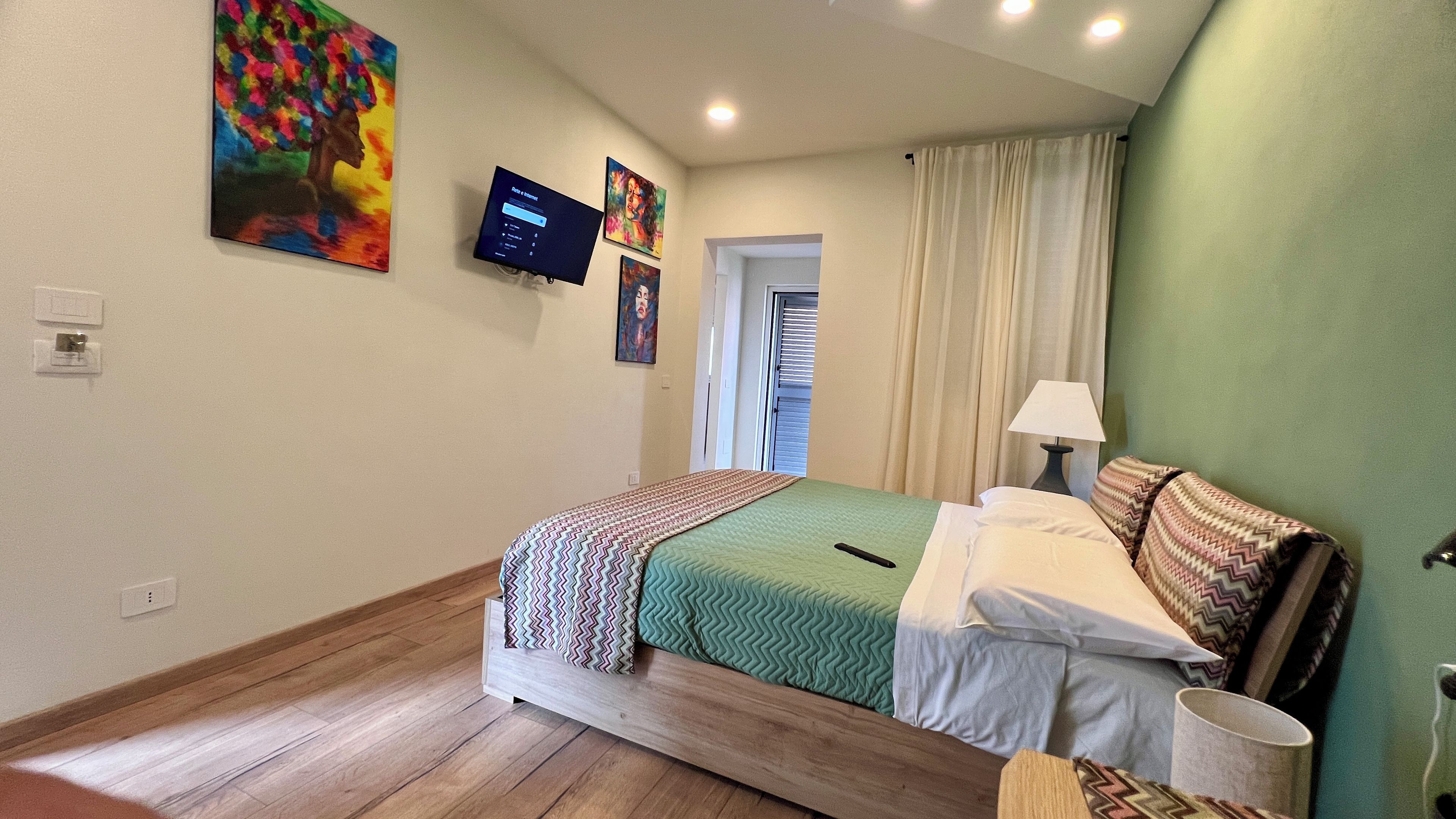 Une chambre d’hôtel avec un lit, une télévision et des œuvres d’art accrochées aux murs.