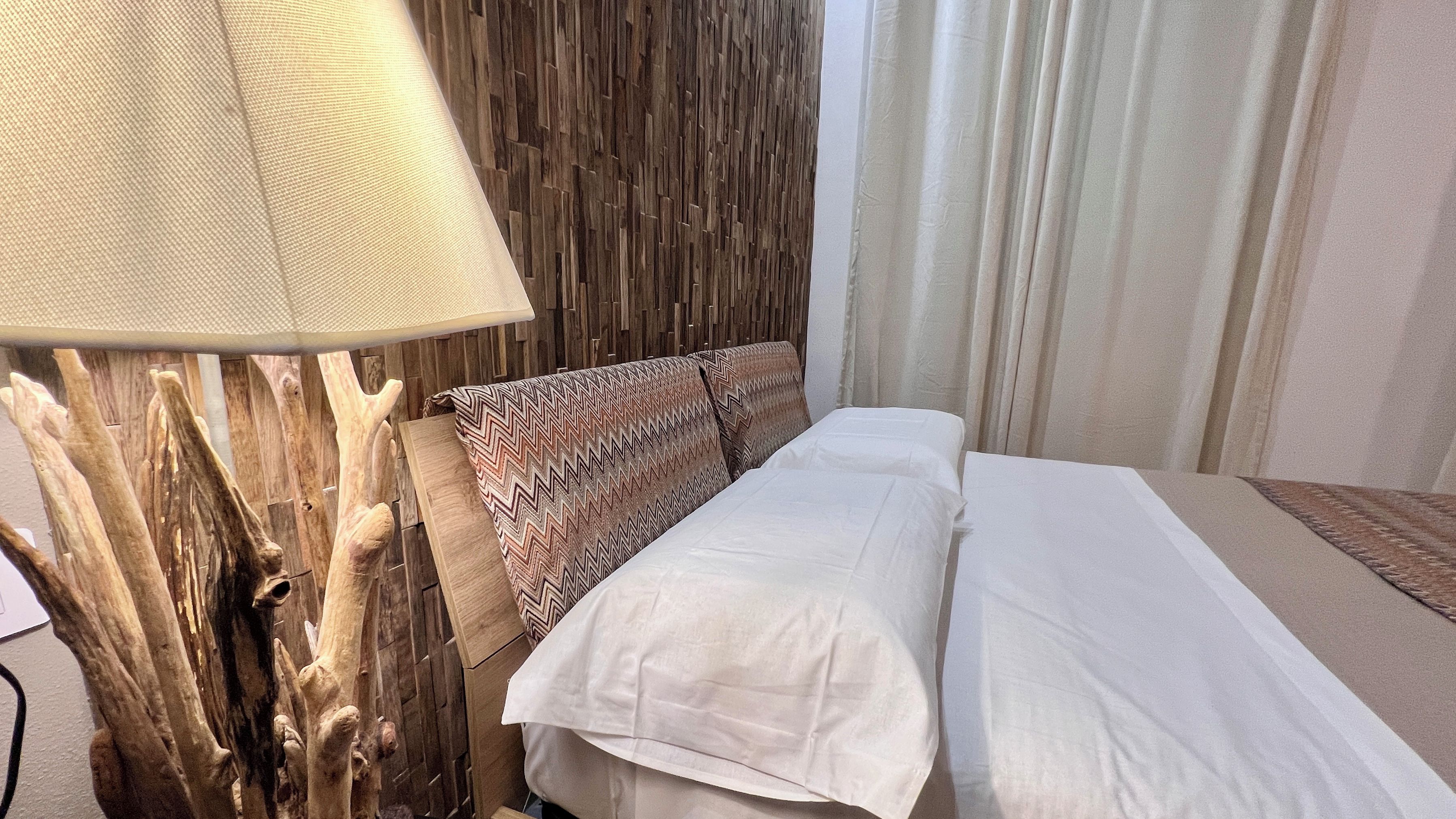 Ein Hotelzimmer mit einem Bett, einer Lampe und einer Holzwand.