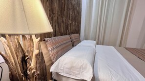 A hotel room with a bed, a lamp, and a wooden wall.