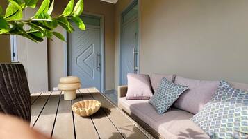 A room with a wicker sofa, a patterned cushion, a bowl, and a door with a geometric design.