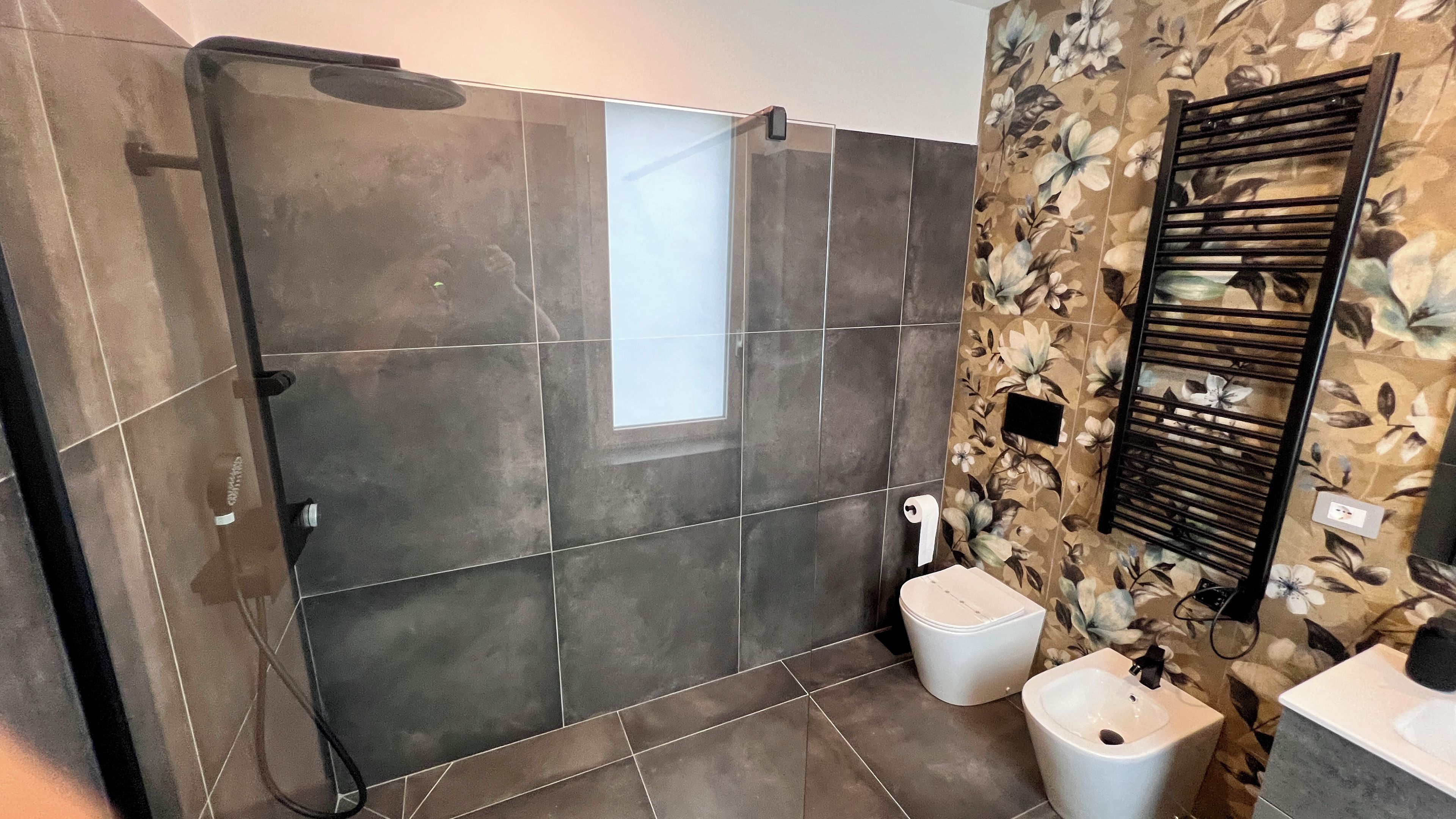 Ein Badezimmer mit Dusche, zwei Waschbecken, Toilette und Handtuchhalter.