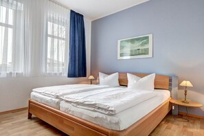 Una habitación de hotel con una cama grande, una mesita de noche, una lámpara y un cuadro en la pared.
