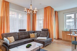 Uma sala de estar com sofá seccional, mesa de jantar e lustre.