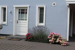A residential building with a white door and windows, a mailbox, and a small garden with pink flowers. - Holiday home in Zingst with swimming pool (Zingst)
