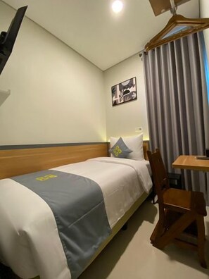 Una habitación de hotel con una cama individual, un escritorio y una silla.