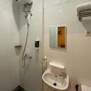 Un baño con ducha, lavamanos y espejo.