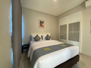 A bedroom with a bed, a wardrobe, and a wall-mounted air conditioning unit. - Ghurfati Hotel Wedana (Jakarta)