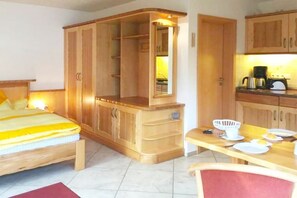 A bedroom with a bed, wooden wardrobe, and a small table with a chair. - 2 in the Lili Marleen House (Ostseebad Prerow)