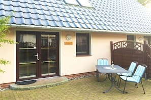 A house with a tiled roof, a front door, and a patio with a table and chairs. - 2 in the Lili Marleen House (Ostseebad Prerow)