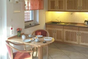 A compact kitchen with a dining area, featuring a sink, cabinets, and a table set for two. - 1 in the Lili Marleen House (Ostseebad Prerow)