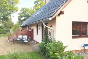 A building with a tiled roof, a covered patio with a table and chairs, and a sign indicating parking availability. - 1 in the Lili Marleen House (Ostseebad Prerow)