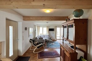 A cozy living room with a sofa, chairs, a television, and a globe on a cabinet. - Holiday apartment with 1 bedroom (Ratzeburg)