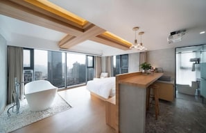 A modern hotel room with a large bed, a bathtub, a kitchen area, and a view of the city. - Serene Nook Hotel  Skyline&River Views (Yuzhong District)