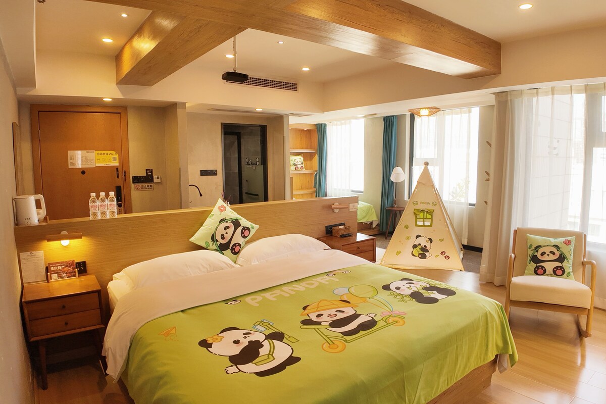 A hotel room with a bed, a nightstand, a chair, a window with curtains, and a wooden ceiling.