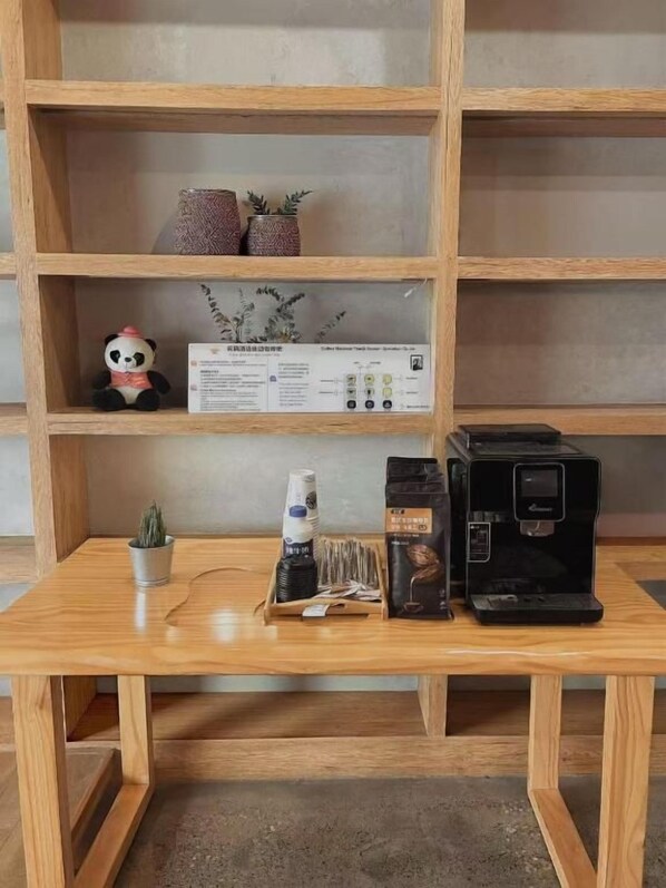 A wooden table with a coffee machine, a small plant, and a panda figurine. - Serene Nook Hotel  Skyline&River Views (Chongqing)