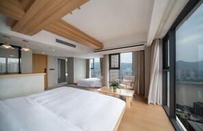 A modern hotel room with a large bed, a seating area, and a city view. - Serene Nook Hotel  Skyline&River Views (Chongqing)