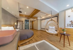 A modern bedroom with a bed, a hanging chair, and a small table with a plant. - Serene Nook Hotel  Skyline&River Views (Chongqing)