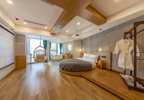 A modern bedroom with a curved bed, a wooden floor, a hanging chair, and a robe rack. - Serene Nook Hotel  Skyline&River Views (Chongqing)