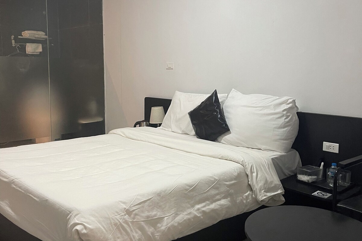 A hotel room with a bed, bedside table, and a small round table.