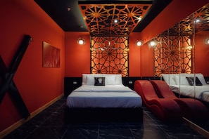 A modern hotel room with a large bed, two red chairs, a decorative ceiling, and a patterned wall. - Atlantis Tran Duy Hung Apartment (Yen Hoa)