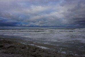Ein Strand mit Wellen und einem bewölkten Himmel.