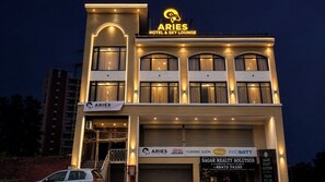 Een hotel met een opvallend bord waarop 'ARIES HOTEL & SKY LOUNGE' staat en een zichtbare ingang.