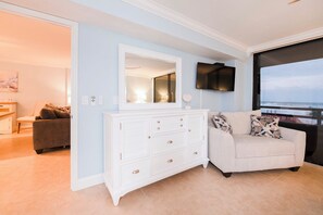 A modern living room with a white dresser, a beige sofa, and a large window offering a view of the ocean. - #102 Seychelles 2/2 Oceanview Traffic Free Beach (Daytona Beach Shores)