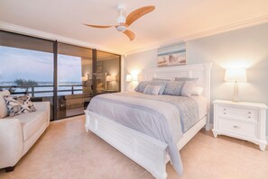 A bedroom with a large bed, a nightstand, a ceiling fan, and a view of the ocean through a sliding door. - #102 Seychelles 2/2 Oceanview Traffic Free Beach (Daytona Beach Shores)