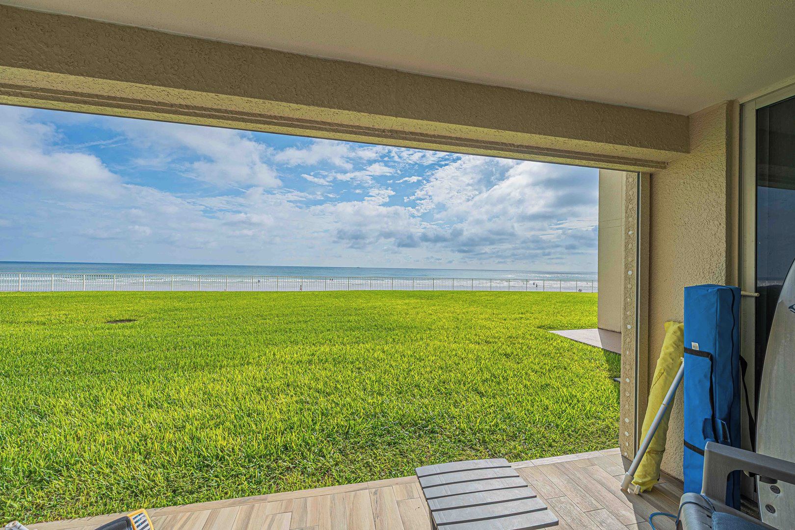 A balcony with a view of a grassy area and a beach.