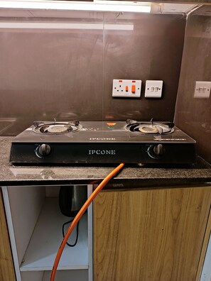 A kitchen with a double electric stove labeled 'IPHONE' and two wall-mounted switches. - Cozy Studio with Gym & Lift Prime location near TRM Mall (Nairobi)