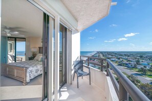 A balcony with a bed, a chair, and a view of a coastal town. - Stunning Million Dollar Views- Seychelles 1106 (Daytona Beach Shores)