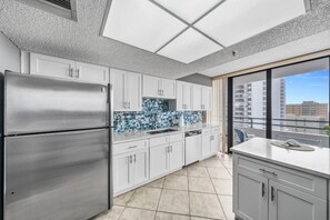 A modern kitchen with a large refrigerator, white cabinets, and a tiled backsplash. - 11D Royal Atlantic 2/2 ocean view unit (Daytona Beach Shores)