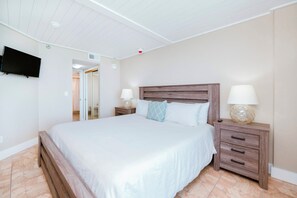 A bedroom with a bed, bedside tables, a TV mounted on the wall, and a ceiling with recessed lighting. - 12th Floor Oceanfront 2/2 with Exceptional Views at 1202 Sand Dollar (Daytona Beach Shores)