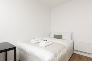 Ein Schlafzimmer mit einem Bett, einem Nachttisch und einer Heizung.