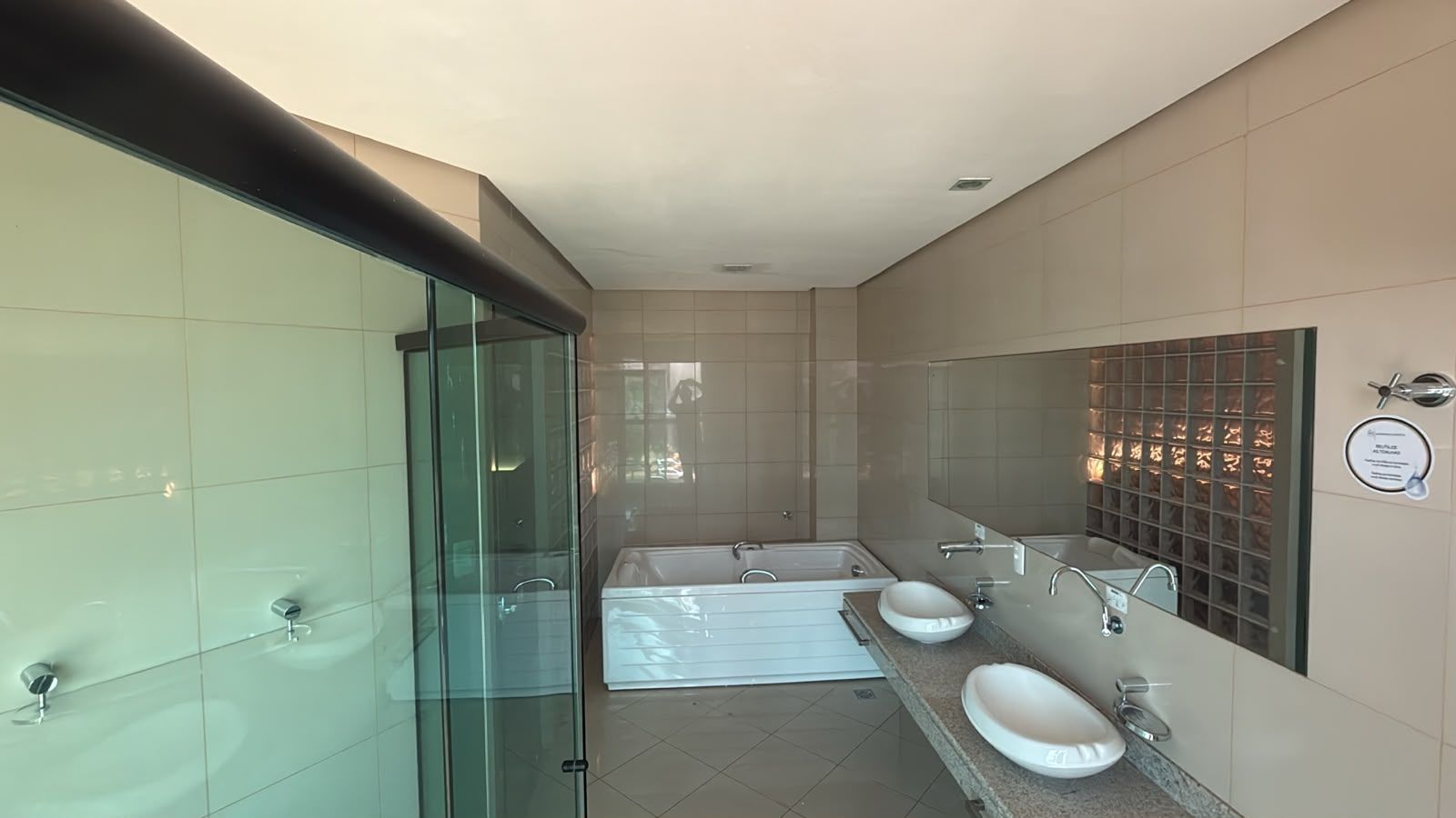 A modern bathroom with a glass shower enclosure, a bathtub, and two sinks.