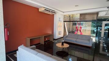 A modern lobby with a grey sofa, a small round table, and a fire extinguisher mounted on the wall.