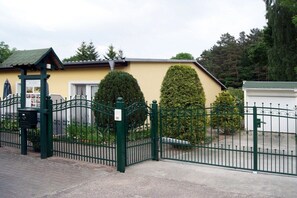 Een omheind landgoed met een gebouw, een groen hek en keurig bijgesnoeide struiken.
