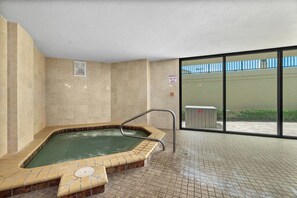 Ein Whirlpoolbereich mit gefliesten Wänden und Boden, einer Metallleiter und einem großen Fenster mit Aussicht.