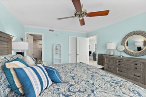 Ein Schlafzimmer mit Bett, Kommode, Deckenventilator und Spiegel.