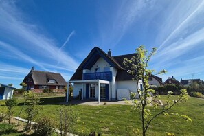 A two-story house with a balcony, a covered porch, and a well-maintained lawn. - Thatched house "Villa Selma" (Zierow)
