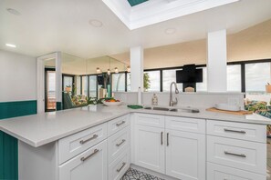 A modern kitchen with white cabinetry, a large island, a built-in oven, and a large window offering a view. - 15B2 Oceans West in Daytona Beach Shores, FL (Daytona Beach Shores)