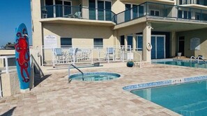 A pool area with lounge chairs and a lifeguard stand. - 1701 Towers Ten in Daytona Beach Shores, FL (Daytona Beach Shores)