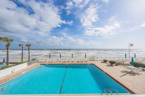 A swimming pool with a view of the ocean, a flag, and lounge chairs. - 1B Royal Atlantic in Daytona Beach Shores, FL (Daytona Beach Shores)